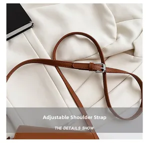 Close-up of brown leather adjustable shoulder strap with silver metal buckle on a bag