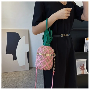 Détail du sac bandoulière rose en forme d'ananas avec rivets et boucle dorée