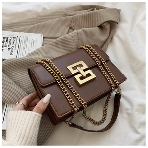 Detail of vintage dark brown leather bag with large gold geometric buckle and chain strap