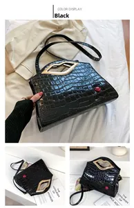 Détail du sac noir façon croco avec poignée lèvre dorée et accessoire lèvre rouge