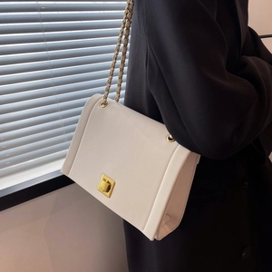 Détail d'un sac bandoulière blanc avec fermoir tournant doré et bandoulière chaîne
