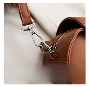Detail of silver lobster clasp and D-ring on brown leather bag with stitching