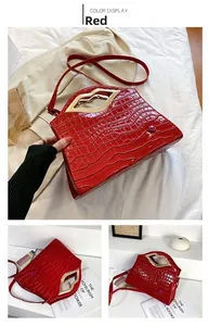 Détail d'un sac à main rouge en similicuir avec motif crocodile et poignée dorée en lèvres