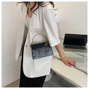 Detail view of marble pattern box bag with gold metal handle and chain strap on model