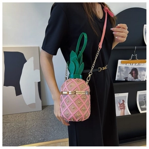 Détail du sac bandoulière rose en forme d'ananas avec poignée feuille et rivets