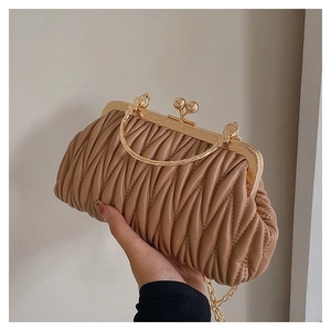 Detail of khaki pleated dumpling bag with golden metal frame and round ring handle