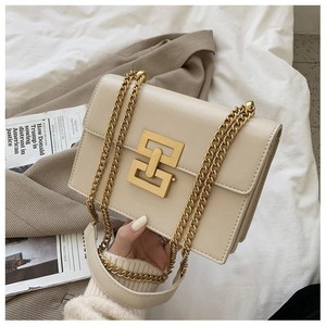 Detail of cream rectangular bag featuring a golden geometric lock and chain strap