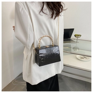 Detail of black marble acrylic box bag featuring a golden bamboo metal handle