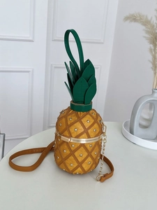 Détail du sac à bandoulière ananas jaune avec clous dorés et poignée en feuilles vertes