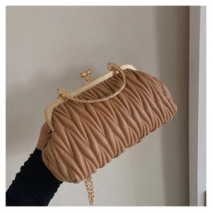 Close-up of caramel pleated leather handbag with ornate gold metal handle and clasp