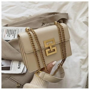 Detail of a creamy white rectangular flap bag with golden geometric lock and chain strap