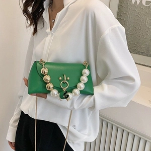 Fashionable green handbag with pearl chain handle and round metal lock shown on model