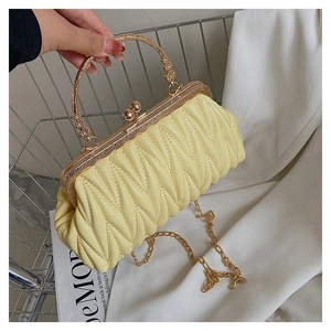 Detail of yellow quilted pleated handbag with gold metal clasp and chain in a shopping basket