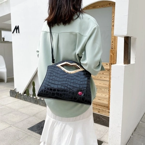 Détail du sac noir à texture crocodile avec poignée dorée en lèvres et imprimé lèvres rouges