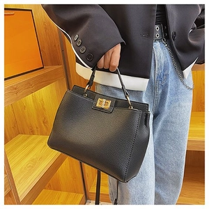 Dettaglio borsa in pelle martellata nera con vistosa chiusura a girello dorata