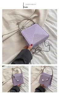 Detail of purple handbag featuring V-shaped embossed texture and silver ring handle