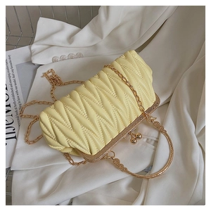 Detail of yellow quilted bag with gold handle and vintage clasp on white fabric
