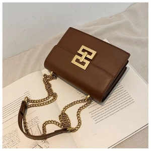 Detailed view of dark brown leather square bag with gold geometric buckle and chain