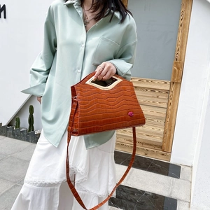 Détail du sac bandoulière croco avec poignée triangle dorée et breloque lèvres rose