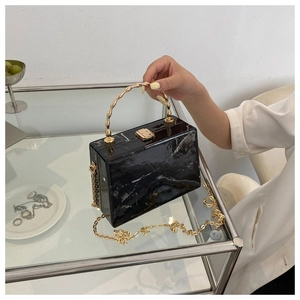 Detail of black marble textured box clutch with gold bamboo handle and chain strap