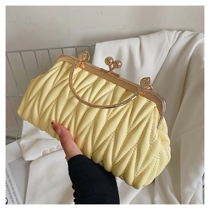 Detail of light yellow ruched cloud clutch bag with gold frame and round handle