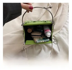Interior capacity view of green mini square bag with silver ring handle and chain strap