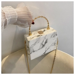 Detail of marble pattern box bag with gold bamboo handle and metallic clasp