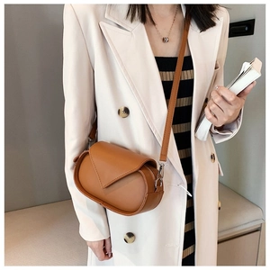 Brown crossbody bag with fine stitching and silver metal buckle on a beige suit jacket