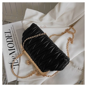 Close-up of black pleated leather crossbody bag with golden chain and ring handle