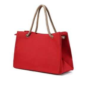 Detailed side view of a red canvas tote bag with thick natural hemp rope handles