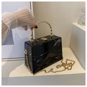 Detail of marble acrylic clutch with gold bamboo handle and metallic chain strap
