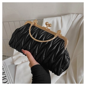 Detail of black pleated clutch with gold metal handle and vintage clasp closure