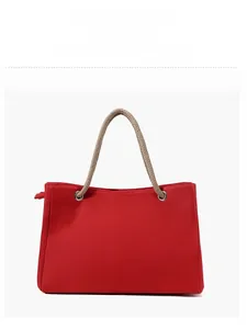 Detail view of large red canvas tote bag with thick rope handles and reinforced metal eyelets
