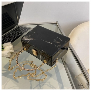 Close-up of elegant black marble texture box bag with gold bamboo handle and chain