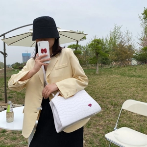 Détail d'un sac à main blanc motif crocodile avec accent lèvres rouges sur l'herbe