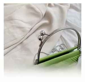 Detailed view of green quilted handbag featuring silver metal handle and bead clasp closure