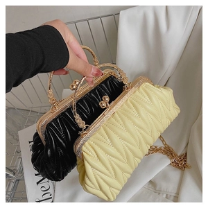 Detail of vintage quilted handbag with carved gold metal handle and chain strap