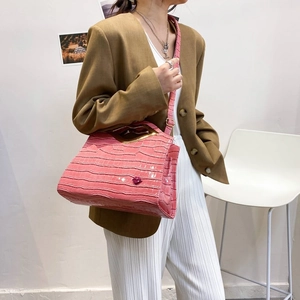Détail du sac à main rose gaufré croco avec poignée dorée et décoration lèvres