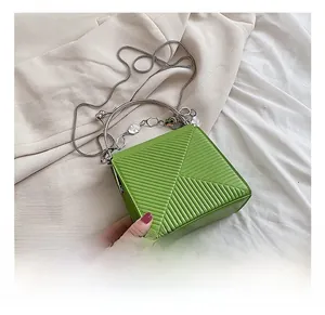 Detail of bright green textured handbag with geometric patterns and silver metal handles