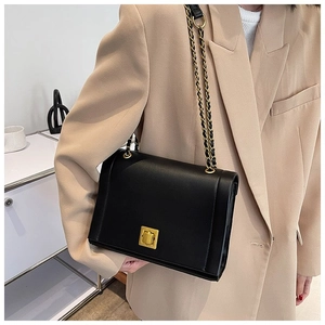Sac bandoulière noir chic avec fermoir doré et bandoulière chaîne sur un modèle