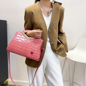 Détail du sac à main rose gaufré croco avec poignée dorée et badge logo lèvres