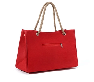Detail of red canvas tote bag featuring thick woven texture and cotton rope handles