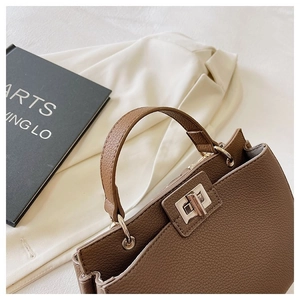 Dettaglio borsa in pelle marrone con trama litchi e chiusura a girello in metallo