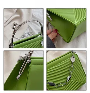 Close-up of green handbag with geometric quilted pattern and silver metallic handle