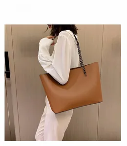 Brown large capacity tote bag with black chain and leather strap shown on a model