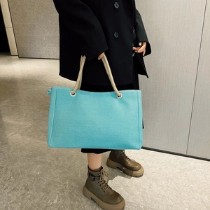 Blue canvas tote bag with thick rope handles shown on a model in a minimalist setting