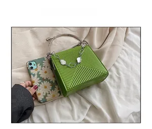 Quilted green handbag with silver metal ring handle and daisy phone for size comparison