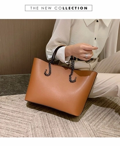 Close-up of brown tote bag with black metal chain handle on textured grey carpet