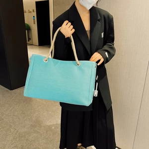 Teal canvas tote bag with thick rope handles shown as a shoulder bag on a model