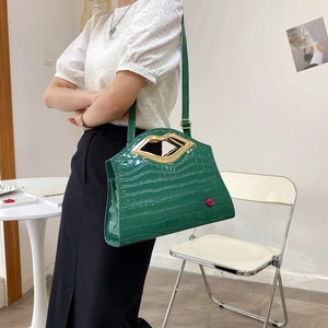 Détail du sac bandoulière vert texture croco avec poignée dorée en forme de lèvres et brillant